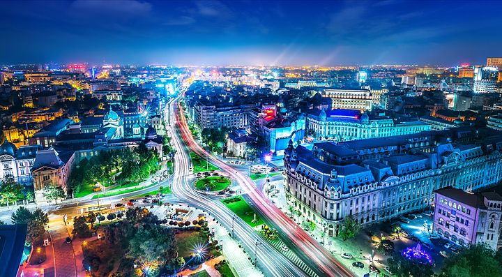 Vista notturna della città di Bucarest con strade illuminate e edifici caratteristici.