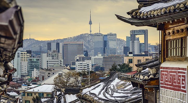 Vista sulla città di Seoul con l'architettura tradizionale in primo piano e la Namsan Tower sullo sfondo.