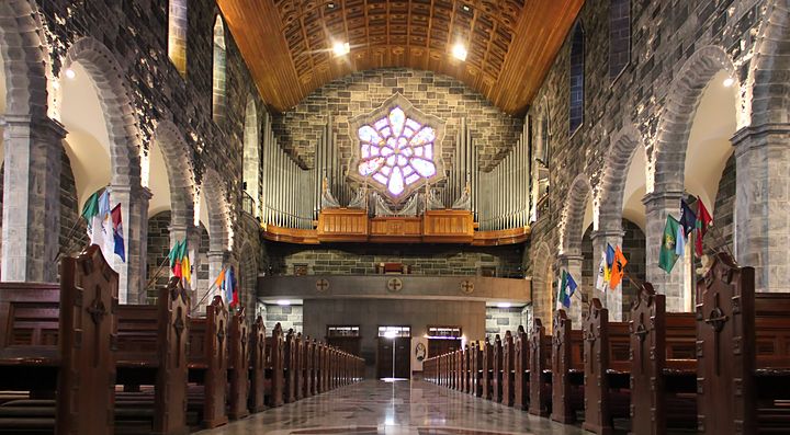 Interno di una chiesa a Galway con vetrate e bandiere.