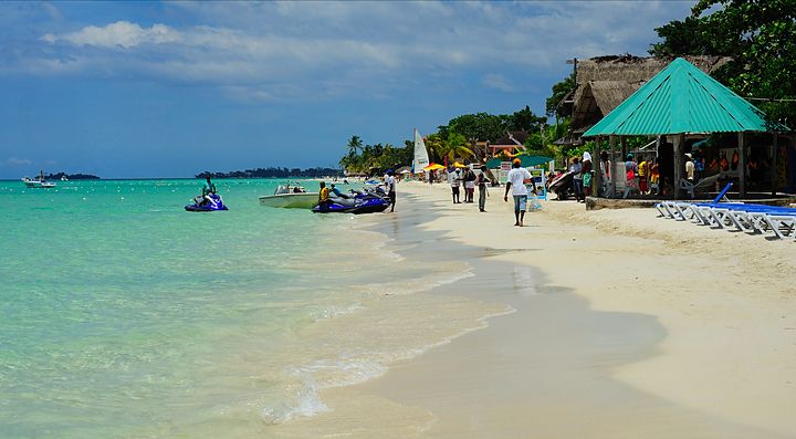 Spiaggia della Giamaica con acque turchesi e capanne di fronte.