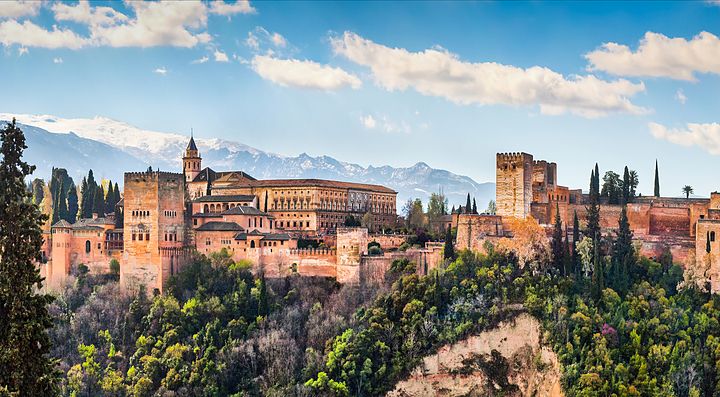 L'Alhambra di Granada circondata da vegetazione e montagne.