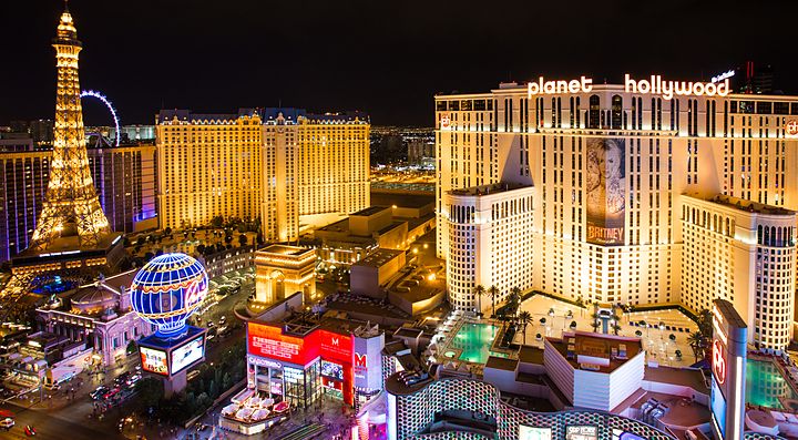 Skyline notturno di Las Vegas con hotel illuminati e Torre Eiffel in lontananza.