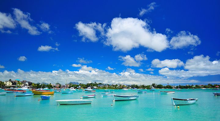 Barche colorate su acque turchesi a Mauritius sotto un cielo blu.