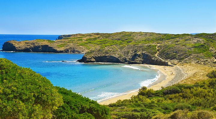 Spiaggia isolata con acque turchesi e scogliere a Minorca.
