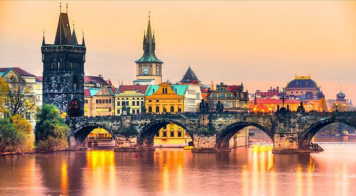 Ponte Carlo a Praga al tramonto con edifici storici sullo sfondo.