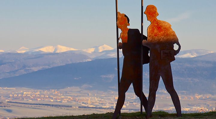 Due sculture di pellegrini sullo sfondo delle montagne a Santiago.
