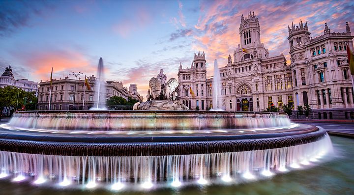 Fontana di Cibeles a Madrid al tramonto con cielo rosa.