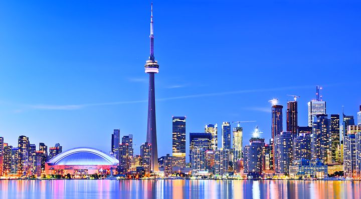 Skyline di Toronto con la CN Tower al tramonto e riflessi sull'acqua.