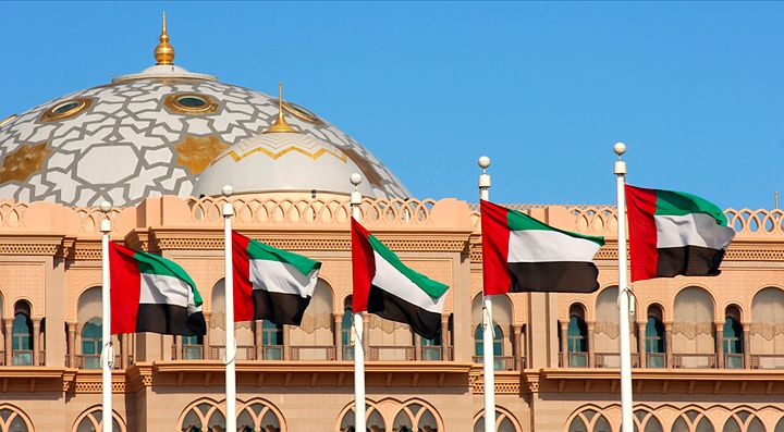 Bandiera degli Emirati Arabi sventola davanti a un edificio con cupola ornata.