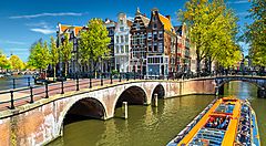 Canale pittoresco di Amsterdam con battello e case tipiche.