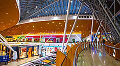 Interno del terminal dell'aeroporto di Kuala Lumpur con negozi colorati.