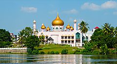 Moschea con cupole dorate in Malesia circondata dal verde.