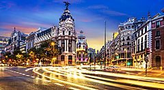 Gran Via di Madrid illuminata al tramonto con traffico in movimento.