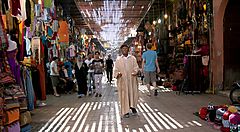 Mercato coperto in Marocco con persone che camminano e bancarelle colorate.