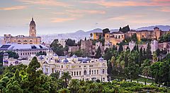 Veduta panoramica di Malaga con edifici storici al tramonto.