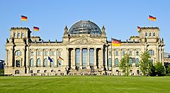 Il Reichstag di Berlino con bandiere tedesche sul prato verde.