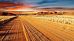 Strada sterrata nel deserto della Namibia al tramonto.