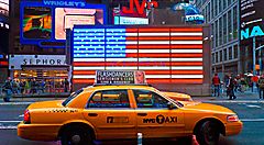 Taxi giallo a New York davanti a una bandiera americana luminosa.