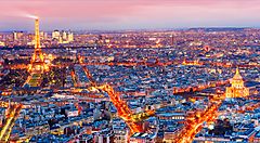 Vista panoramica di Parigi al tramonto con la Torre Eiffel illuminata.