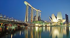 Skyline notturno di Singapore con Marina Bay Sands e ArtScience Museum riflessi nell'acqua.