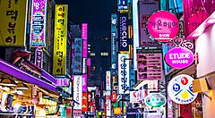 Strada di Seoul illuminata da luci al neon colorate durante la notte.