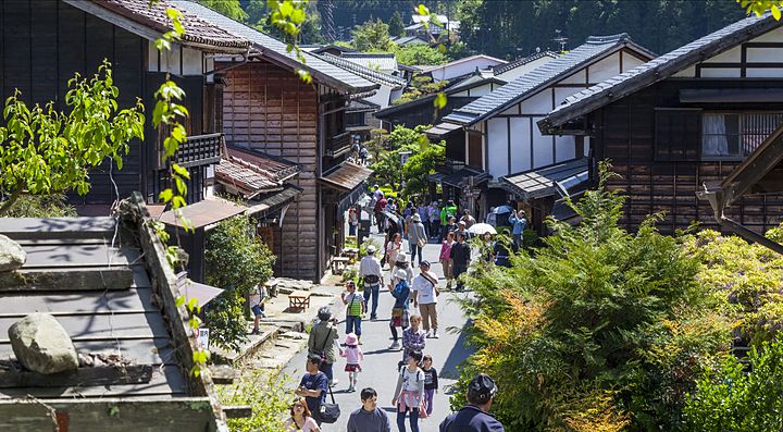 Strada fiancheggiata da case tradizionali in Giappone con persone che passeggiano.