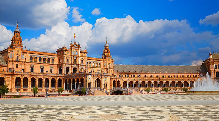 Plaza de España a Siviglia illuminata dal sole con cielo blu e nuvole.