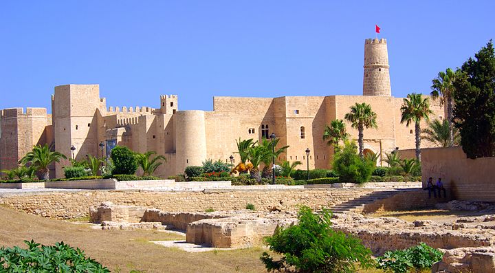 Fortezza storica in Tunisia con palme e mura sabbiose.