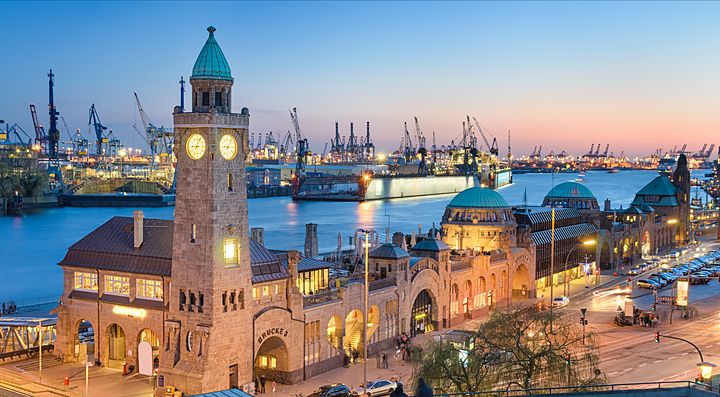 Vista serale del porto di Amburgo con edifici storici illuminati.