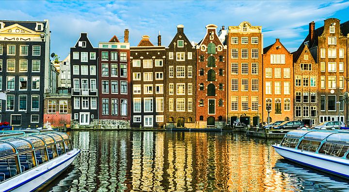 Edifici storici e canali riflessi nell'acqua ad Amsterdam.