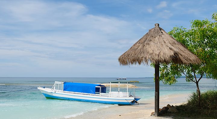 Spiaggia delle isole Gili con barca e capanna di paglia.