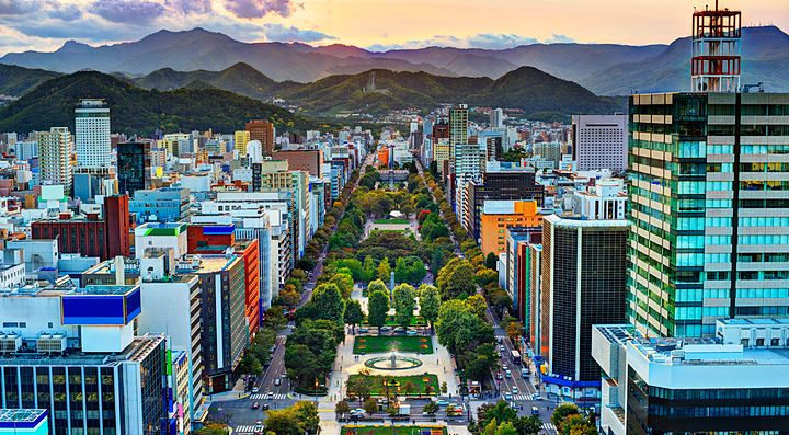 Vista panoramica del Parco Odori a Sapporo, tra edifici e montagne sullo sfondo.