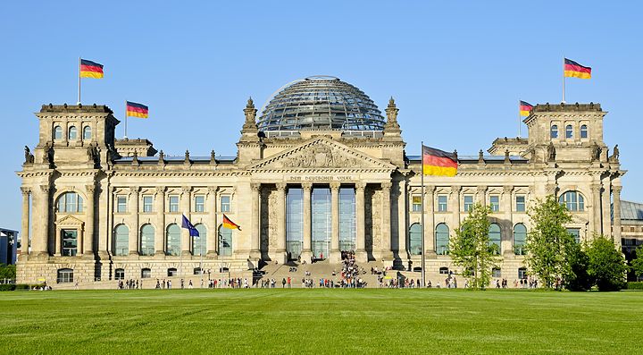 Il Reichstag di Berlino con bandiere tedesche sul prato verde.