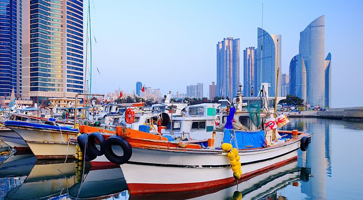 Barche nel porto con grattacieli sullo sfondo a Busan.