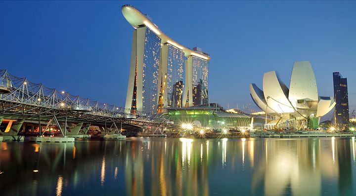 Skyline notturno di Singapore con Marina Bay Sands e ArtScience Museum riflessi nell'acqua.