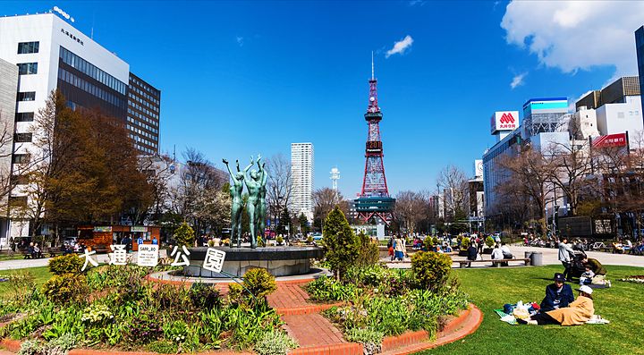 La Torre della TV di Sapporo vista da un parco con persone e edifici.