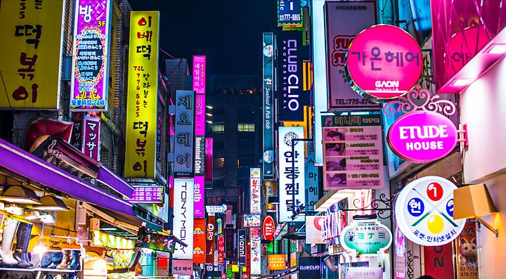 Strada di Seoul illuminata da luci al neon colorate durante la notte.