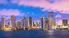 Skyline di Miami al tramonto con edifici illuminati e cielo colorato.