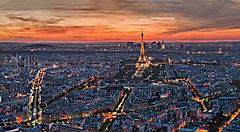 Vista panoramica di Parigi al tramonto con la Torre Eiffel illuminata.