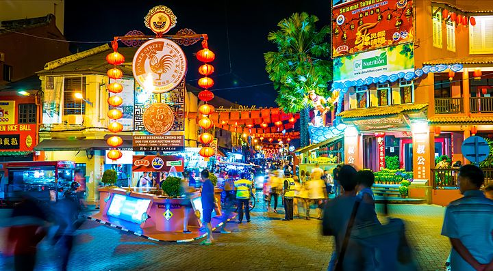 Strada animata di notte a Malacca con lanterne rosse e negozi illuminati.