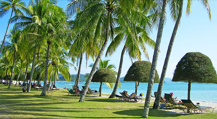 Spiaggia tropicale a Langkawi con palme e sedie a sdraio.