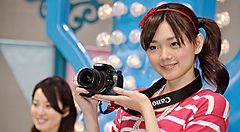 Persona sorridente tiene una fotocamera Canon in un ambiente luminoso.