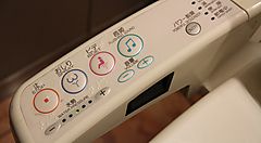 Pannello di controllo di un WC giapponese con icone e pulsanti colorati.