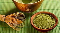 Polvere di matcha, una tazza e l'utensile per mischiare e preparare il tè matcha.