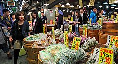 Bancarelle di cibo al Nishiki Market a Kyoto, con clienti che passeggiano.