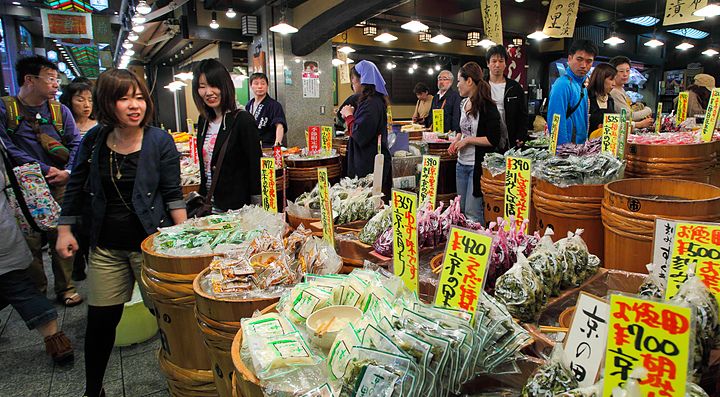 Bancarelle di cibo al Nishiki Market a Kyoto, con clienti che passeggiano.