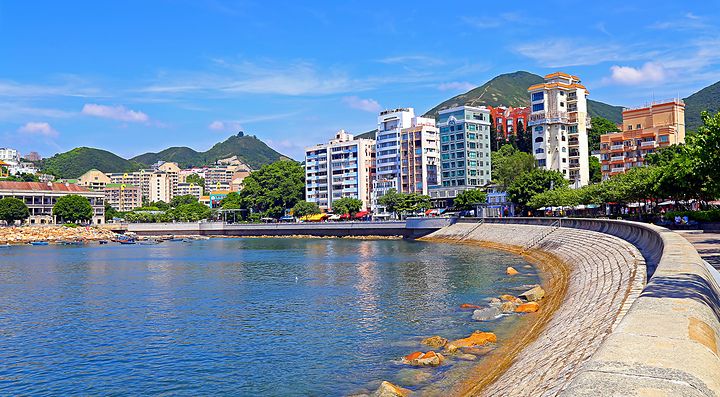 La costa urbana di Stanley, Hong Kong, con edifici e colline sullo sfondo.