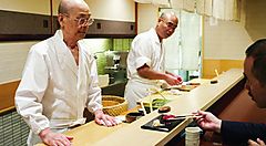 Jiro, la leggenda del sushi, mentre cucina dietro al bancone nel suo ristorante.