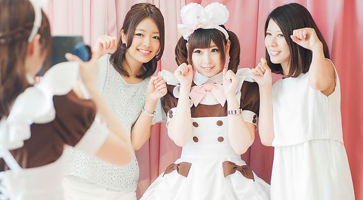 Gruppo di persone in un cafe, una vestita da cameriera in costume kawaii.
