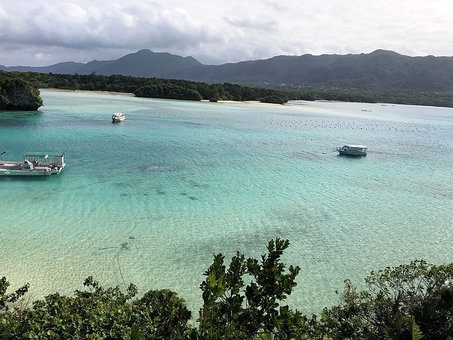 Veduta aerea della baia di Kabira con barche, mare cristallino, isole e montagne sullo sfondo.